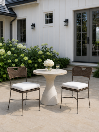 Outdoor patio set with two chairs and a table on a patio in front of a house.